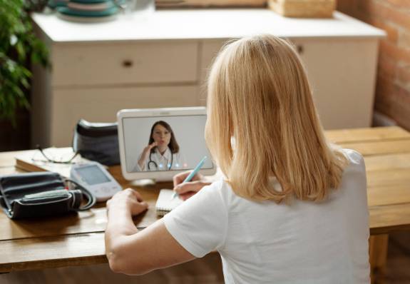 Patientin spricht über Laptop mit Arzt