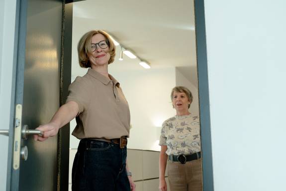 Frau öffnet anderer Frau die Tür