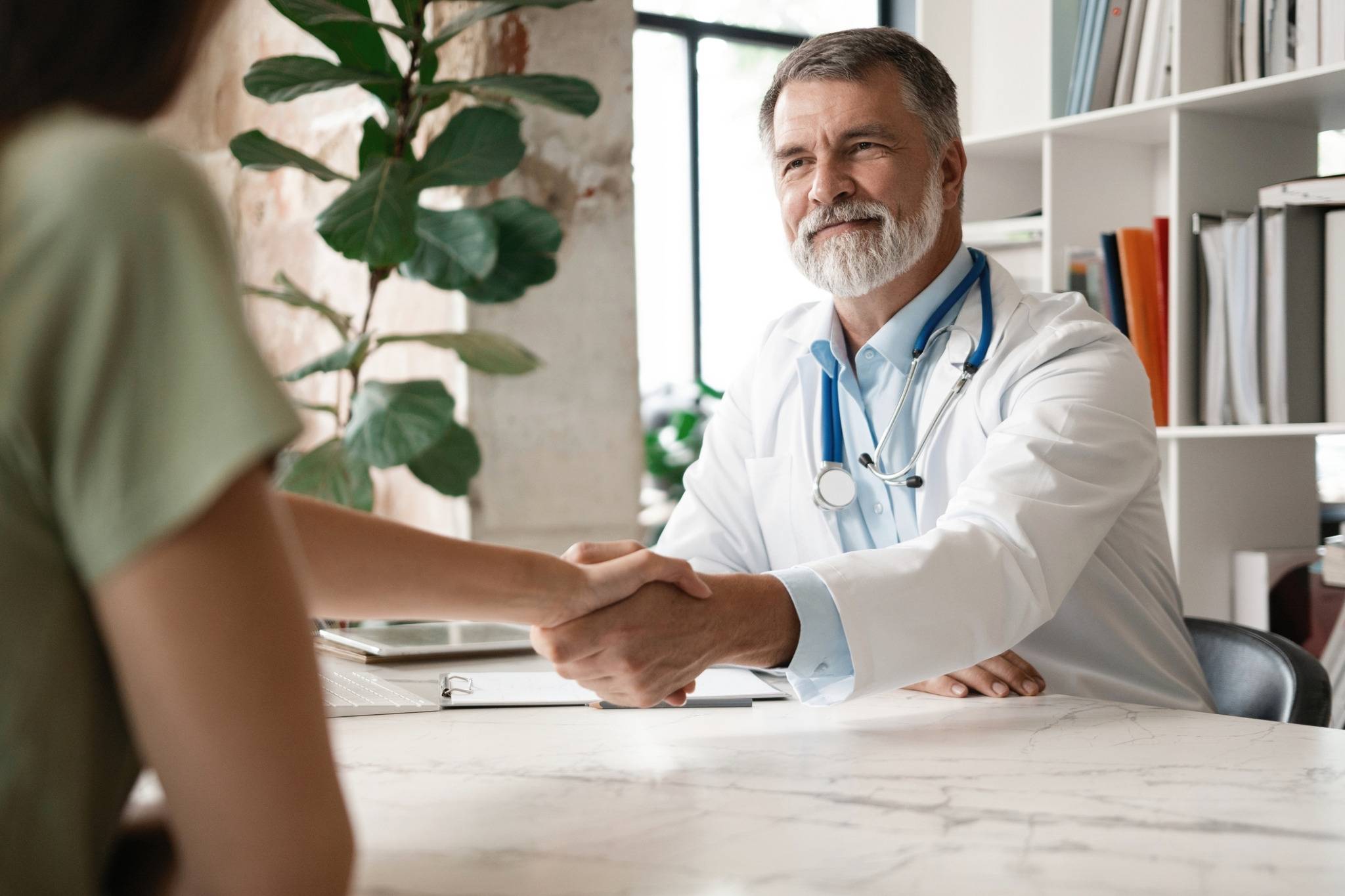Arzt und Patientin geben sich die Hand